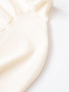 Macro shot of cream wool knit fabric showing fine ribbed texture and detailed edge finish