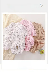 Detailed flat lay of floral muslin baby rompers with matching sun hats in three soft colors