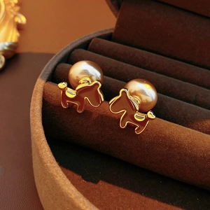 Macro shot of 18K gold plated puppy earrings with large pearls on brown velvet