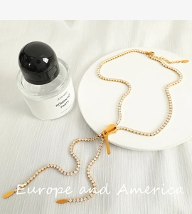 Macro detail of gold rhinestone zipper necklace on white tray with perfume bottle