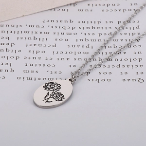 Detailed view of an oval stainless steel pendant featuring a carnation flower engraving