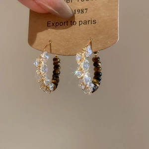 Detail of tiger eye stone and crystal earrings on a display card with gold hooks