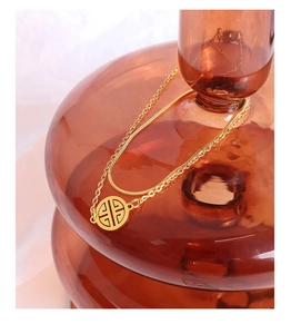 Close-up of a double-layered 18K gold-plated snake chain necklace with hollow round pendant