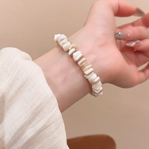 Detailed close-up of irregular off-white geometric shell beads on an elastic bracelet