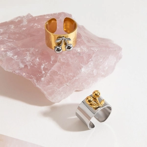 Detail showing two-tone cherry charms on polished adjustable wide metal band rings