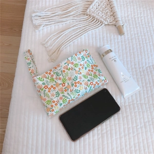 Macro detail of floral cotton pouch with wristlet on white quilted fabric