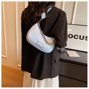 Close-up of light blue underarm bag with gold chain strap on a stylish woman