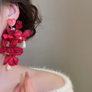 Nahaufnahme von Vintage-Blumenohrringen in Rot mit Quasten und weißen Perlen