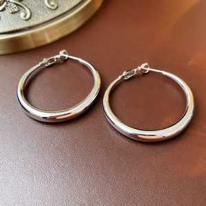 Macro view of polished silver metal hoop earrings on a textured leather surface