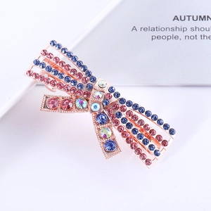 Close-up of sparkling pink and royal blue rhinestone bow hair clip with rose gold base