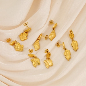 Détail de boucles d'oreilles en titane doré sur soie avec motifs de paume et d'abeille