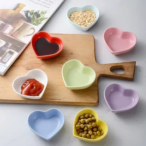 Set of heart-shaped ceramic sauce dishes in vibrant colors on a marble surface