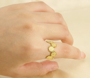 Close-up of a 18k gold wave-shaped stainless steel ring worn on a finger