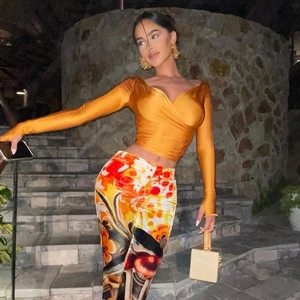 Détail du haut court orange sexy à col en V et du pantalon ajusté imprimé sur les marches