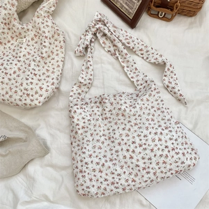Close-up detail of a white floral canvas tote bag featuring a cute bow-tie shoulder strap