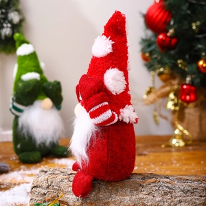 Close-up of red Christmas gnome plush ornament with white beard on wooden base