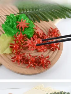 Detailed view of realistic red PVC octopus keychain with textured tentacles on a wooden tray