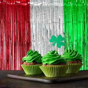 Three green cupcakes against a festive red, white, and green tinsel curtain backdrop
