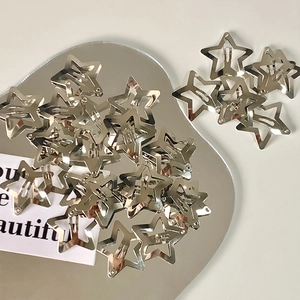 Close-up of shiny silver star-shaped metal hair clips on a reflective heart mirror