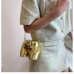 Detail of artistic gold metallic mini crossbody bag with human torso shape and chain