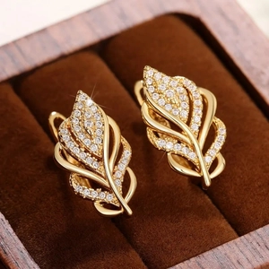 Close-up of gold wheat ear leaf earrings with sparkling zircons in a wooden jewelry box