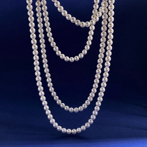 Detail showing elegant multi-layer white pearl necklace over deep blue velvet backdrop