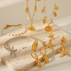 Close-up of golden ocean jewelry set with pearls on beige stone featuring starfish and shells