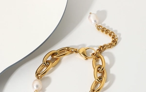 Détail d'un bracelet gourmette en acier doré 18K avec breloque en perle baroque ronde