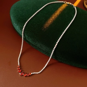 Close-up of a silver necklace with five red gemstones and tiny zircons on velvet
