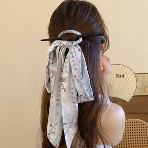 Detailed view of light blue printed silk scrunchie and black hair pin for updo styles