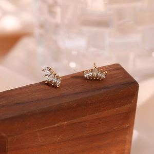 Detail of gold floral stud earrings with marquise-cut zircons on a dark wood stand