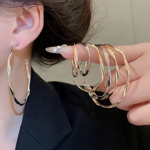 Detail of twisted hoop earrings in gold and silver showing multiple sizes and textures