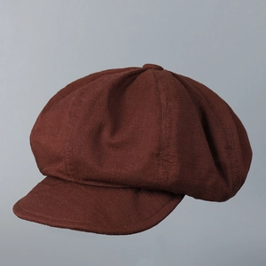 Gros plan détaillé montrant le tissu en lin texturé de la casquette gavroche marron