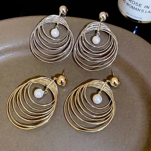Golden and silver multi-layer circle hoop earrings with center pearl on ceramic tray