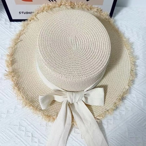 Detail view of woven raffia sun hat featuring a large ribbon bow and stylish frayed edges