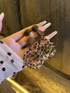 Detail of round leopard print earrings with resin layers and glossy brown studs