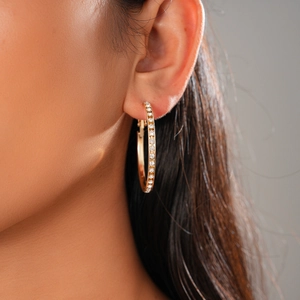 Close-up of gold hoop earring with sparkling pavé zircons worn on model ear