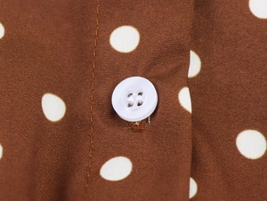 Detail der braunen Polka-Dot-Stoff mit einem matten weißen Knopf und feiner Baumwolltextur