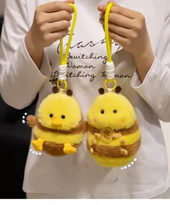 Close-up of cute bee plush keychain with yellow lanyard and lucky golden coin charm