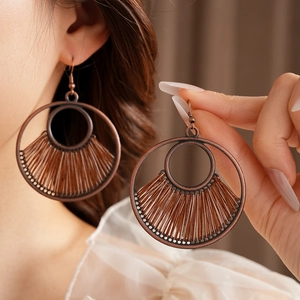 Detail of vintage bronze round fringe earrings with woven fan-shaped tassel design