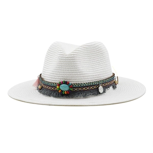 Detail of white straw hat with ethnic rainbow band, turquoise stone, and tassel accents
