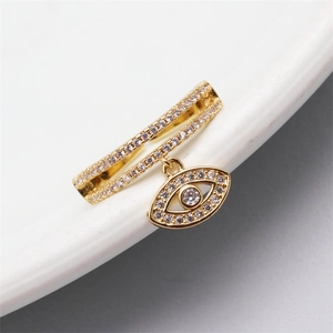 Macro shot of gold double-band ring with evil eye pendant and micro-set crystals