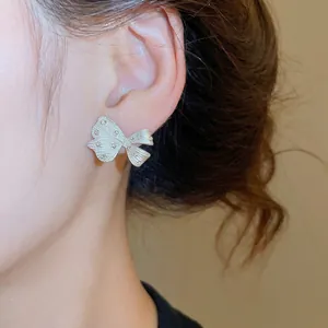 Elegante silberne Schleifen-Ohrstecker mit Kristallen, getragen von einem Modell