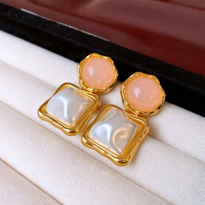 Close-up of vintage gold earrings with pink resin stone and square baroque pearl detail