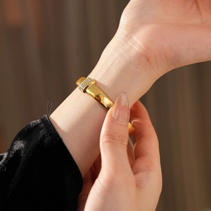 Gros plan d'un bracelet jonc en acier titane doré avec zircone sur un poignet de femme