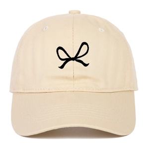 Beige cotton baseball cap featuring black ribbon bow embroidery and classic six-panel design