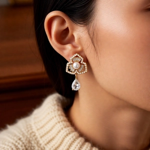 Detail of gold floral pearl drop earrings with teardrop crystal on a female model