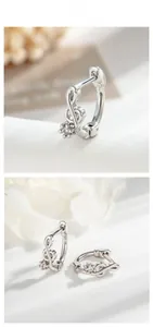 Macro detail of silver G-clef musical note earrings with a small zircon stone inlay