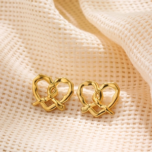Close-up of 18K gold-plated stainless steel pretzel earrings on beige fabric