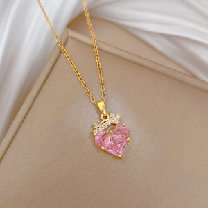 Macro view of gold heart pendant with pink gemstone and sparkling crown detail